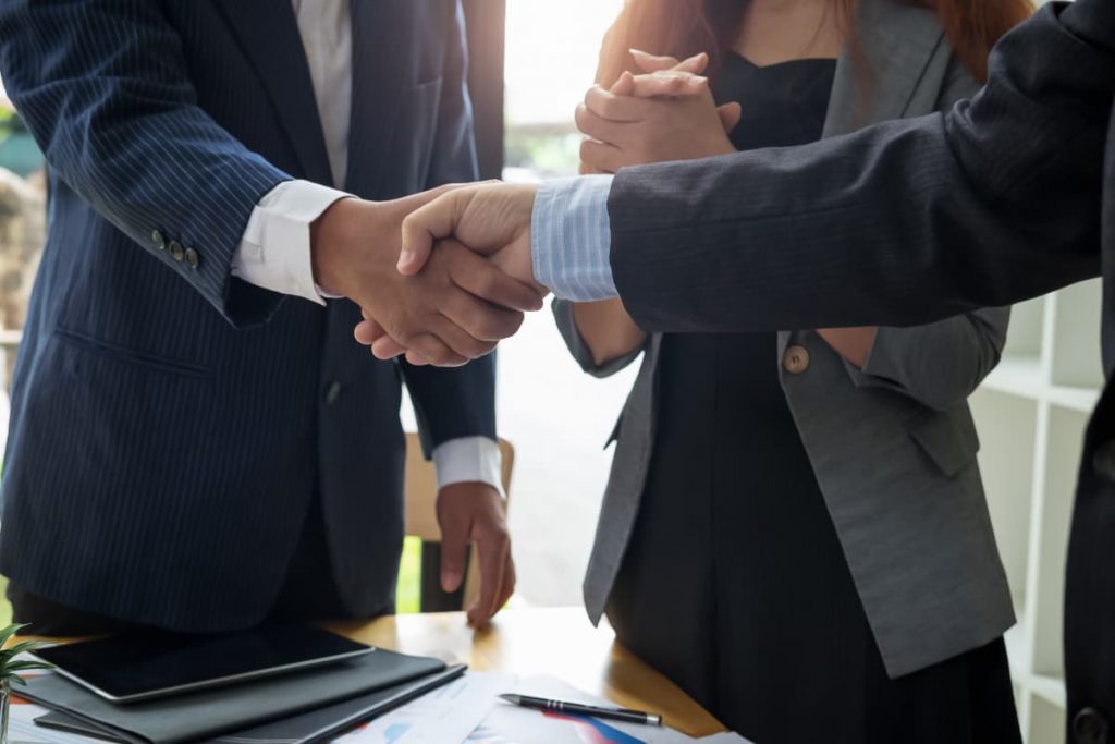 Due professionisti aziendali siglano un accordo stringendosi la mano durante una riunione al tavolo.