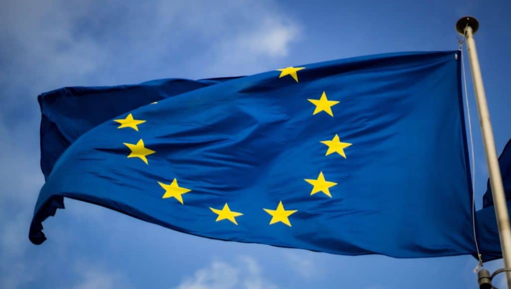 La bandiera dell'UE sventola contro il cielo azzurro con il logo FESR.