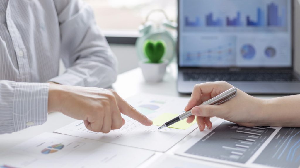 Incontro consultivo con due persone che analizzano documenti e grafici.