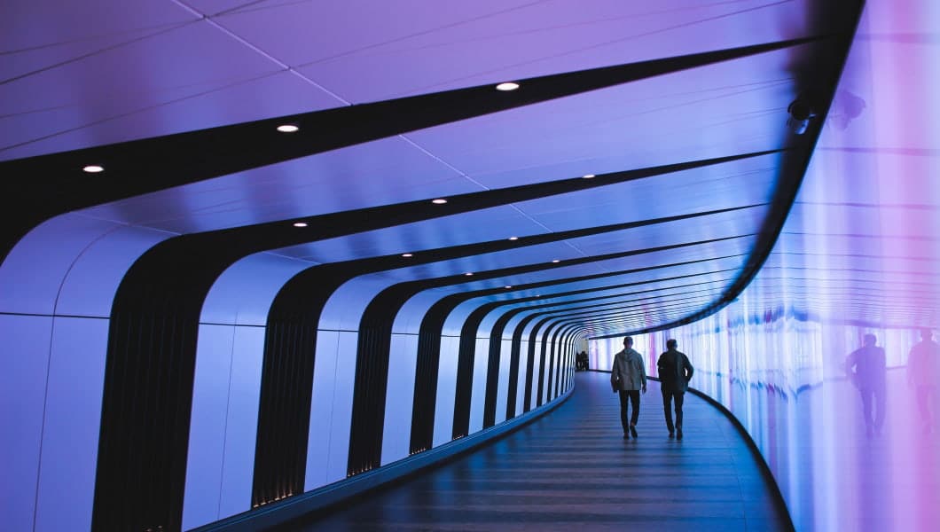 Due persone esplorano un tunnel illuminato da luci vibranti nel Lazio.