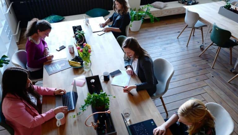 Un gruppo di donne che lavora a un tavolo in un ufficio, concentrandosi sull'assunzione di dipendenti donne.