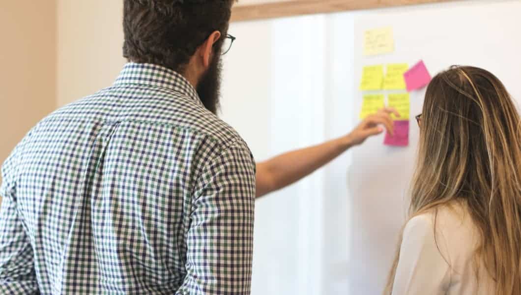 due imprenditori con post it alla lavagna bianca per Innoaid Puglia